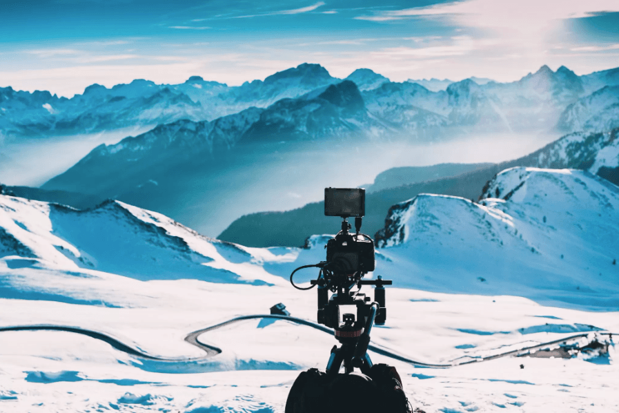 Bilde som illustrerer noen som fotograferer snøkledde fjell. 